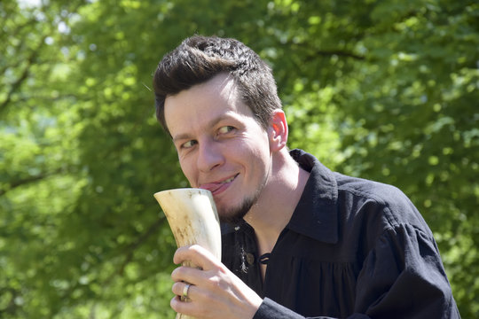 naughty young man drinks from a drinking horn