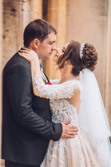 Beautiful fairytale newlywed couple hugging near old medieval castle. Wedding day for adorable newlyweds couple. Man and woomen hug and kiss aech other near old ancient door.