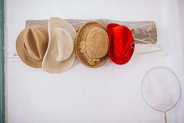 Straw Hats for summer hanging on white wall in hotel. Accessories and travel concept.