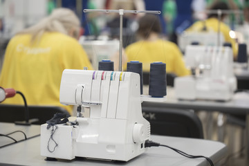 Professional overlock sewing machine with black thread in workshop.