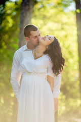 Fototapeta premium Beautiful pregnant woman with her husband in green garden