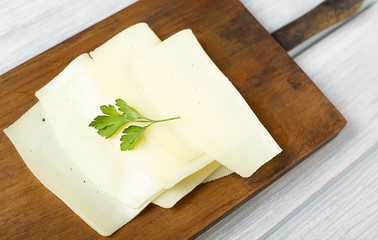 Slices of cheese on wooden board. Food