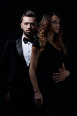 elegant man and woman posing next to each other on studio.