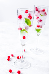 frozen red berries in ice cubes with mint in glasses on stone ba