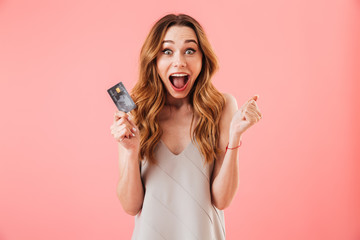 Shocked brunette woman in dress holding credit card