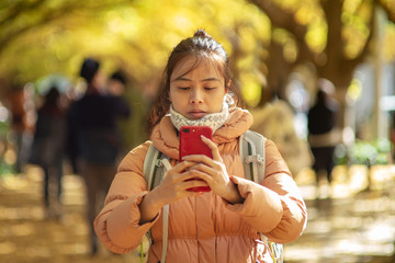 A traveler girl  setting smartphone for mobile photography at Jingu at Gaien Ginkgo Avenue