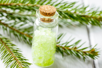 cosmetic spruce salt in bottles with fur branches on white woode