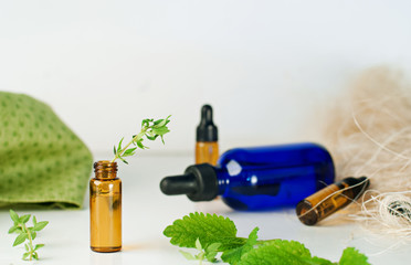 Brown and blue bottles of essential oil with fresh mint and thyme