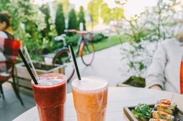 Healthy eating and summer concept. Two glasses of smoothies and snacks on a wooden table of a cafe summer terrace.