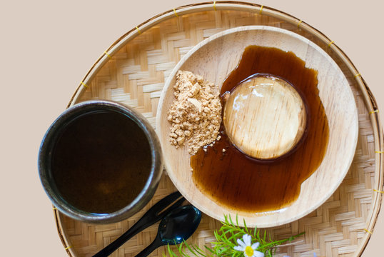 Japanese transparent mochi on wooden plate with sweet sauce, sugar and tea mug taken from top view, isolated