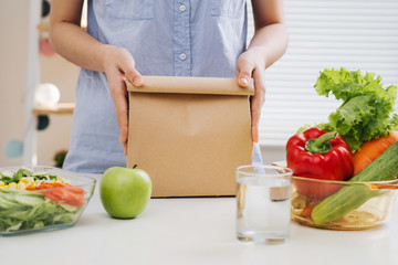 Mother preparing sandwich for school lunch on table