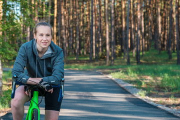 Girl on a bicycle in a grey hoodie in the park. Races on a bicycle. Active way of life and playing sports.