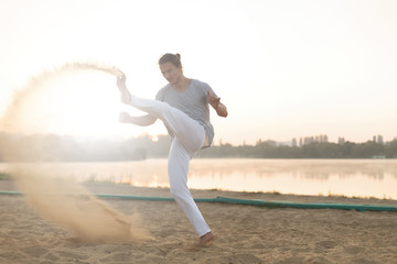 Fototapeta na wymiar Athletic capoeira performer workout training on the beach sunris