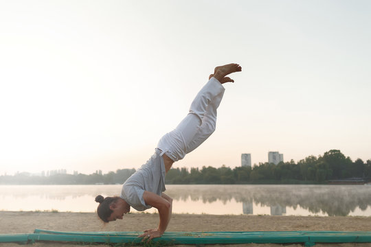 Young athletic man doing yoga poses near the lacke