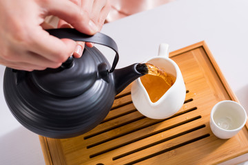 partial view of woman pouring tea into jug while having tea ceremony at home