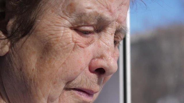 Closeup Of The Sad Face Of An Old Woman Suffering From Tremor Shaking Eyelids
