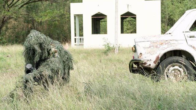 Sniper preparing his sniper rifle in urban combat training ground. Chinese soldier in full ghillie suit slowing preparing his sniper position in urban combat training ground. Anti-terror concept.