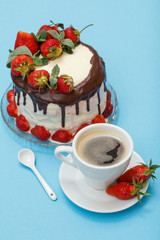 Homemade chocolate cake decorated with fresh strawberries on glass plate and cup of coffee with saucer