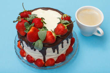 Homemade chocolate cake decorated with fresh strawberries on glass plate and cup of coffee