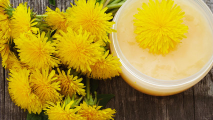 Cosmetic cream with dandelion extract on wooden background.