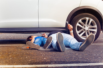 Father and son working under broken car together