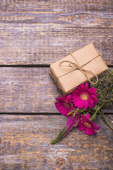 A box with a gift, a bouquet of red flowers on a wooden old background.