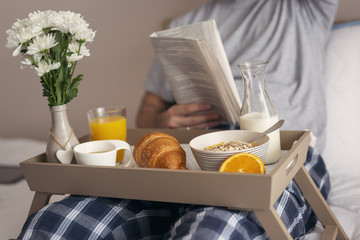 Man reading newspapers and having breakfast in bed