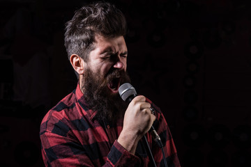 Talent show concept. Man with tense face holds microphone,