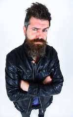 Man with beard and mustache on strict face looking at camera. Macho wears leather jacket, white background. Hipster looks serious while posing in stylish outfit. Menswear and fashion concept.