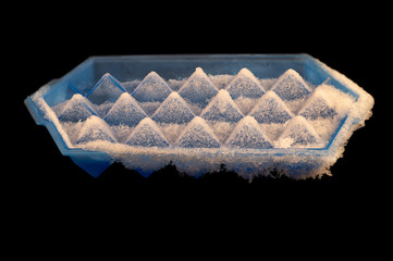 Blue plastic container with frozen ice cubes on a black background.