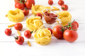 Pasta Products with Tomato Cheese Raw Pasta Fusili Fettuccine Ingredients Italian Food White Background Close Up Copy Space
