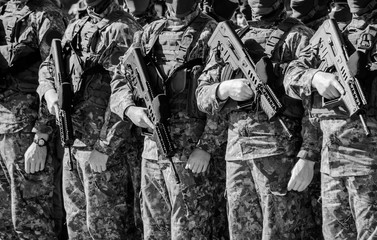 Unrecognizable soldiers in military uniform and in masks standing in a row with guns in their hands at the ceremony. Concept of defending the Motherland