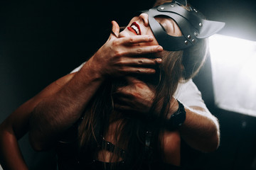 sexy girl in mask and leather belt. sexy girl in a pair of waistcoats.erotica.sexy brunette in a mask.sexy girl in the mask smiles. - obrazy, fototapety, plakaty