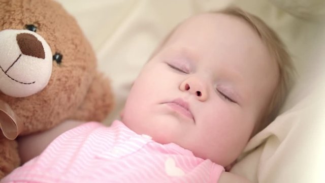 Adorable baby sleeping in bed. Close up of infant girl sleeping with toy. Sweet child face in crib. Dream time for toddler. Kids lullabies. Bedtime concept. Portrait of sleeping baby