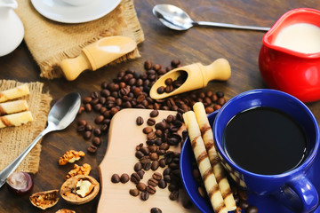 cup and coffee beans. a jug of milk. wooden background.