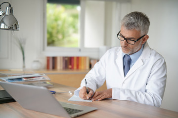 Doctor in office writing medical prescription