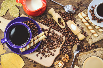 cup and coffee beans. a jug of milk. wooden background.