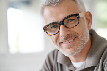 Portrait of smiling middle-aged man with eyeglasses - obrazy, fototapety, plakaty
