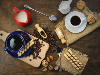 cup and coffee beans. a jug of milk. wooden background.