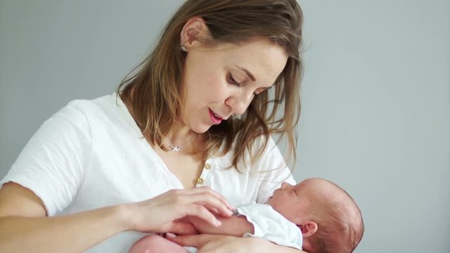 A middle-aged woman is rocking her newborn baby, gently holding his hand. Surrogate motherhood. In vitro fertilization