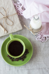 On a light background there is a cup of coffee and a bottle of milk. Next is a craft notebook and a pink napkin.