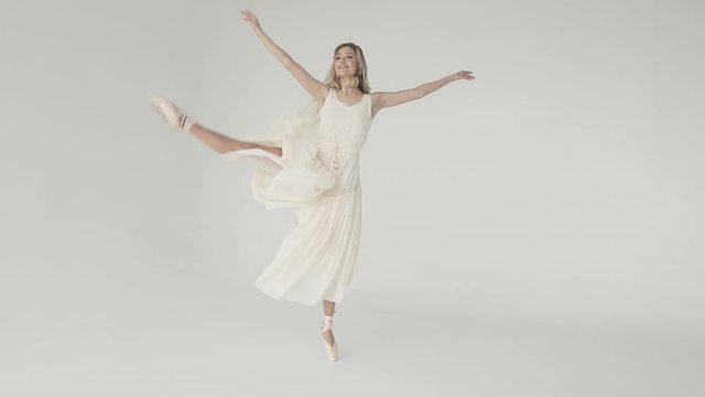 silhouette of ballerina in classical tutu in the white studio. graceful ballerina in a light flying dress dances on tiptoes in pointe shoes. ballet dancer dancing on white background. slow motion