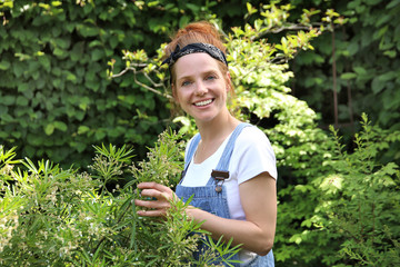 Hübsche rothaarige Frau arbeitet lächelnd in ihrem Garten
