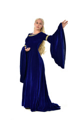 Naklejka premium full length portrait of pretty blonde lady wearing a blue fantasy medieval gown. standing pose on white background.