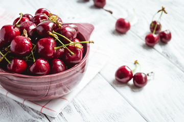 Cherries in colour bowl and kitchen napkin.