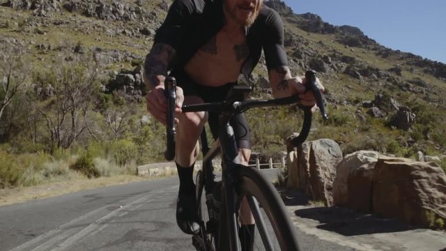 Fit  and healthy cyclist riding fast through mountain road. Man during intense bicycle ride training on a mountain road. 
