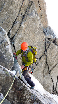 male mountain climber traverses a tricky rock chimney on his way to a high alpine summit