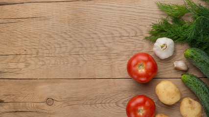 Vegetables, tomatoes, cucumbers, potatoes, dill, garlic on a wooden background with empty space for writing