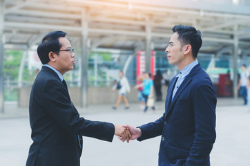 attractive business man shaking hand for complete deal together business successful at outdoor in city. teamwork concept. partnership concept and dealership concept.