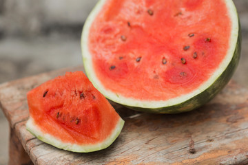 ripe watermelon cut and slices lie on an old wooden stool, rustic style, selective focusing